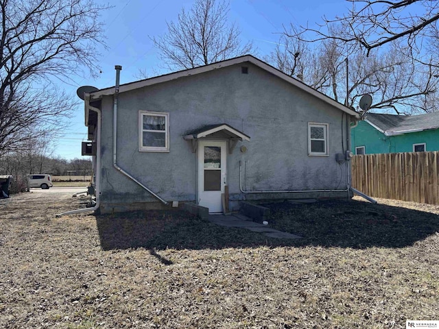 rear view of property with fence and stucco siding