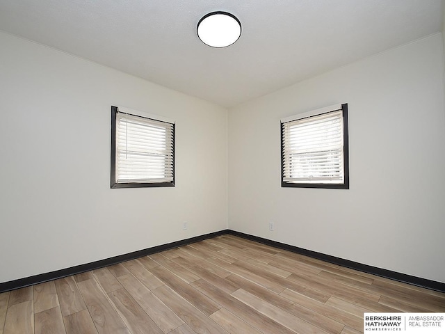 unfurnished room with light wood-style flooring, baseboards, and a wealth of natural light