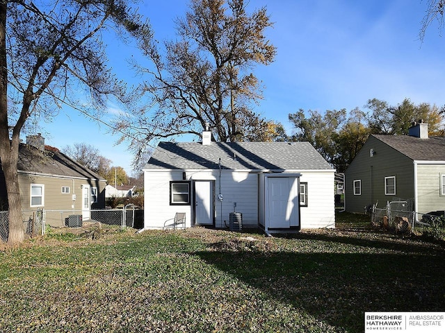 back of house featuring central AC, a lawn, fence, and roof with shingles