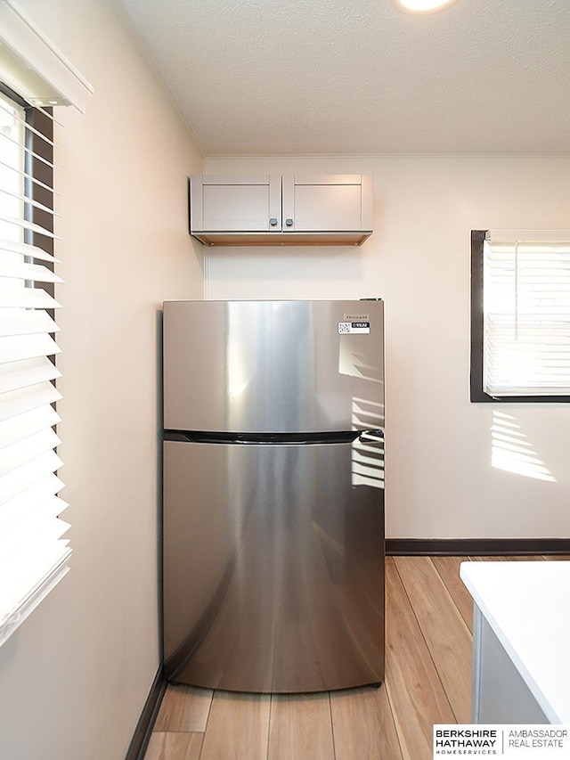 kitchen featuring a healthy amount of sunlight, a textured ceiling, freestanding refrigerator, and light wood-style floors