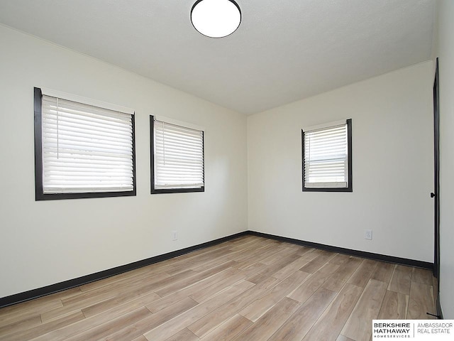 empty room with baseboards and light wood finished floors