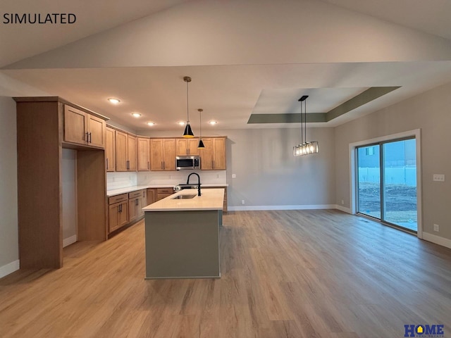 kitchen with a sink, light countertops, stainless steel microwave, and baseboards