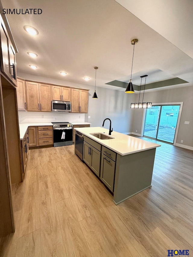 kitchen featuring a sink, light countertops, light wood-type flooring, a center island with sink, and stainless steel appliances