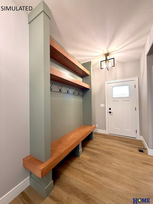 mudroom featuring baseboards, light wood-style floors, and a textured ceiling