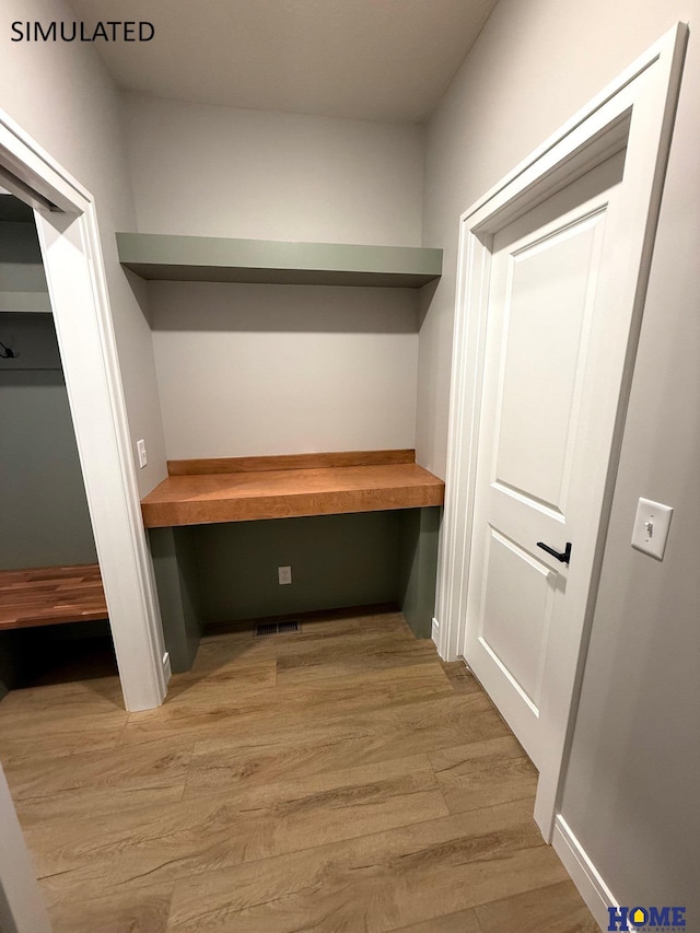 mudroom featuring light wood-style flooring, built in study area, and visible vents