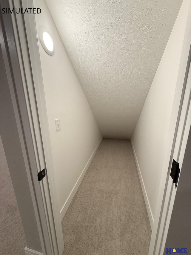 corridor with a textured ceiling, carpet flooring, and baseboards