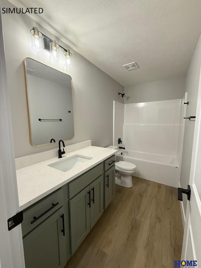 bathroom with vanity, toilet, shower / bathtub combination, visible vents, and wood finished floors