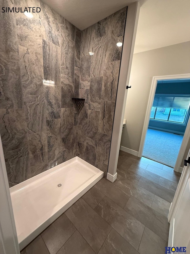 full bathroom featuring baseboards and tiled shower