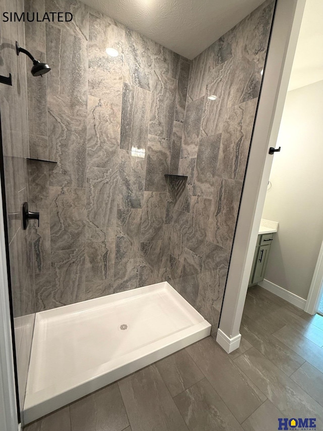 bathroom featuring vanity, baseboards, and a tile shower