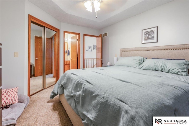 carpeted bedroom featuring ensuite bathroom, a ceiling fan, visible vents, and a closet