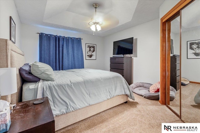 bedroom with a ceiling fan, a tray ceiling, and carpet