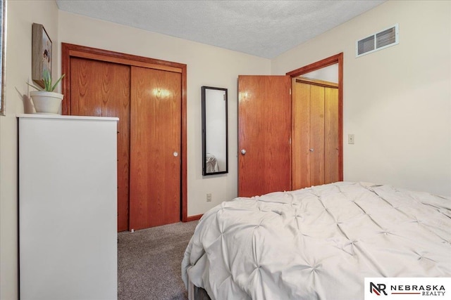 bedroom featuring visible vents, carpet, a closet, and a textured ceiling