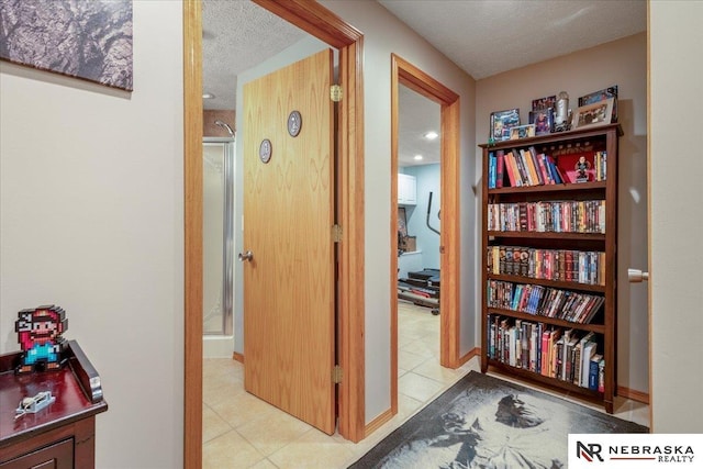 corridor featuring tile patterned flooring, baseboards, and a textured ceiling