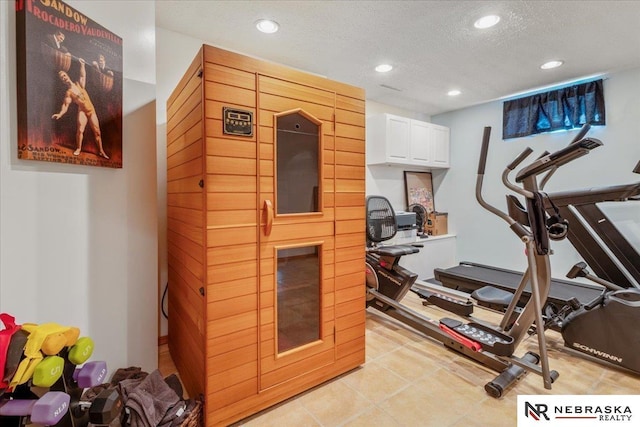 exercise room featuring light tile patterned floors, recessed lighting, and a textured ceiling