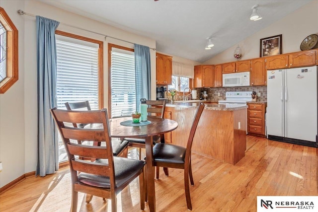 kitchen with white appliances, a peninsula, lofted ceiling, decorative backsplash, and light wood-style floors