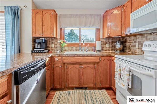 kitchen featuring white appliances, visible vents, a sink, decorative backsplash, and light countertops