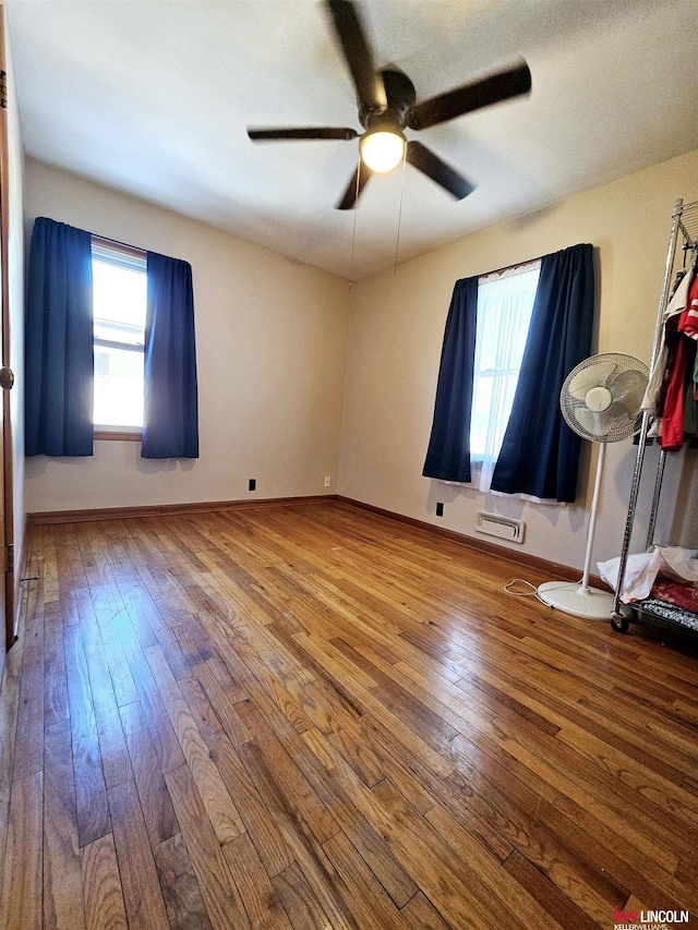 empty room featuring a wealth of natural light, baseboards, and wood-type flooring