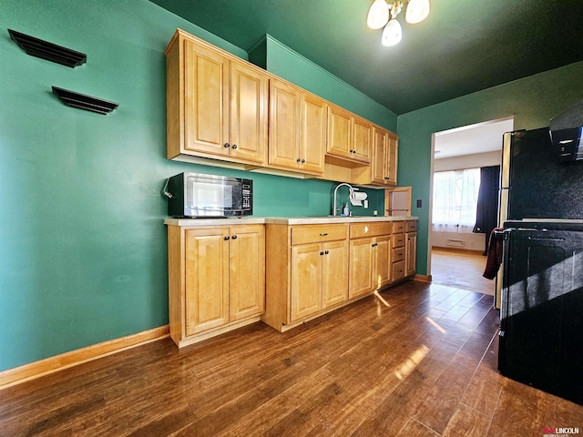 kitchen featuring light brown cabinetry, light countertops, dark wood-type flooring, and black microwave