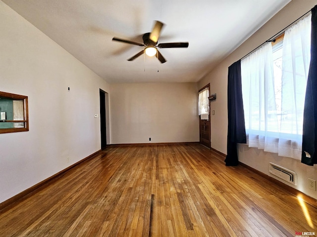 empty room featuring hardwood / wood-style floors, baseboards, and ceiling fan