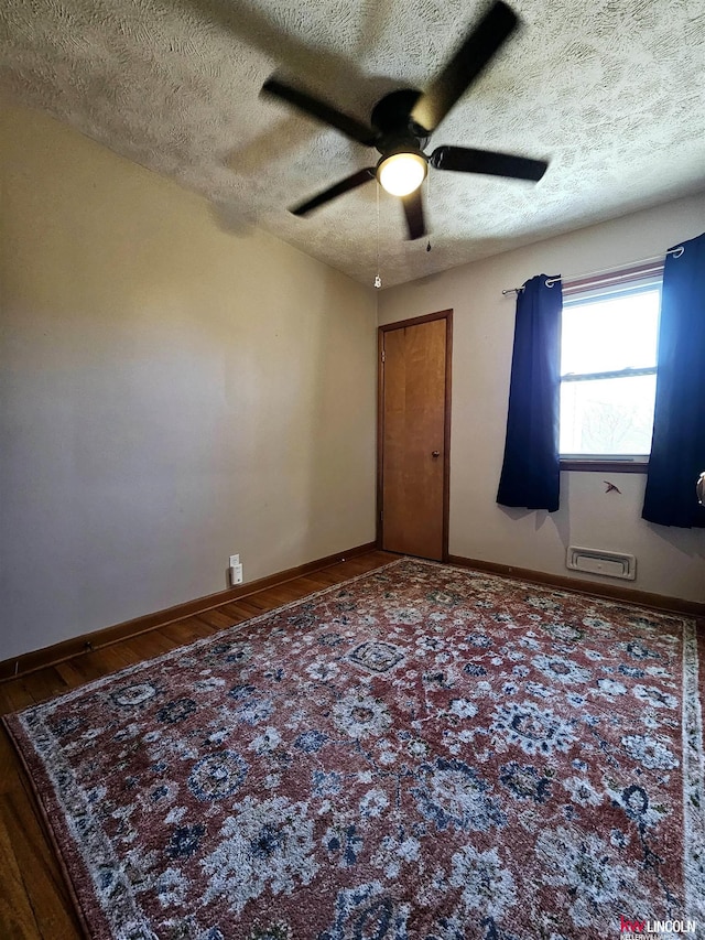 spare room featuring a textured ceiling, baseboards, and wood finished floors