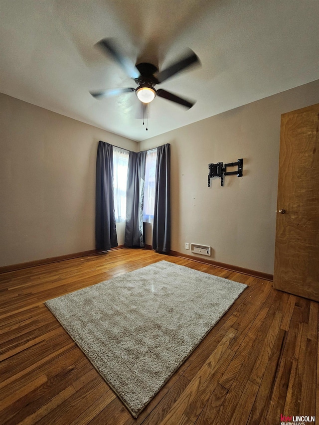 unfurnished room with hardwood / wood-style flooring, a ceiling fan, baseboards, and visible vents