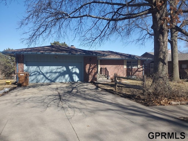 view of front of house with driveway, brick siding, and an attached garage