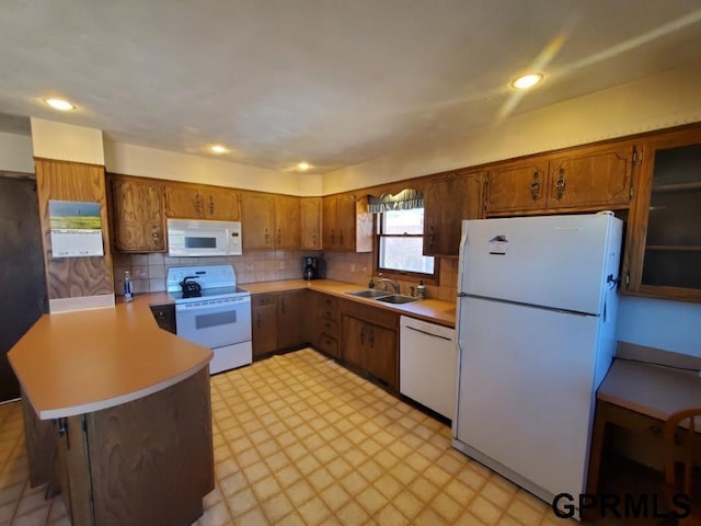 kitchen featuring light floors, light countertops, a peninsula, brown cabinetry, and white appliances