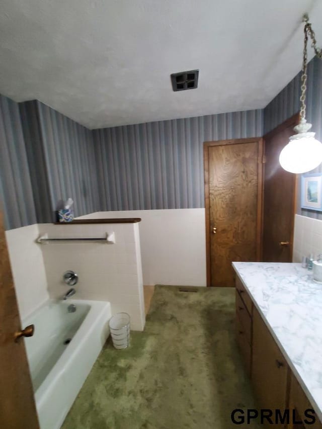 bathroom featuring a bath, visible vents, wallpapered walls, and vanity