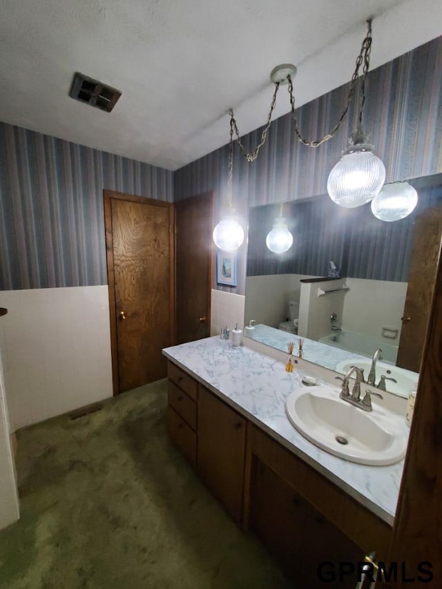 bathroom with visible vents, toilet, wallpapered walls, and vanity