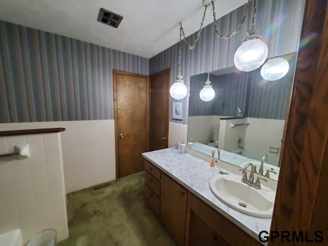 bathroom featuring visible vents, wallpapered walls, and vanity