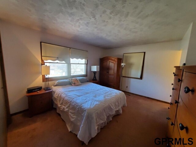 bedroom with baseboards, a textured ceiling, and carpet