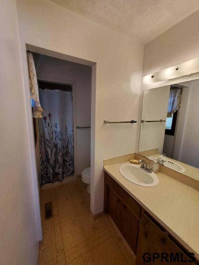 full bathroom featuring tile patterned floors, toilet, a textured ceiling, a shower with shower curtain, and vanity