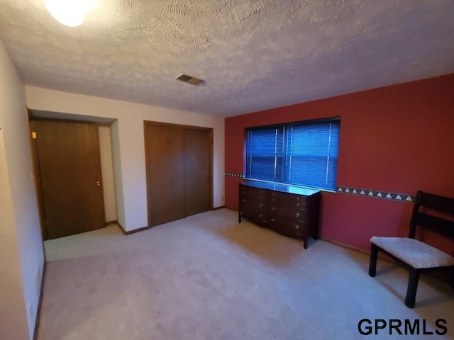 unfurnished bedroom with a closet, visible vents, a textured ceiling, and carpet