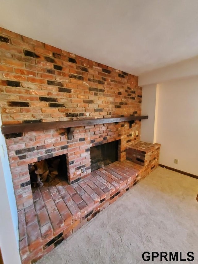 interior space with a brick fireplace, carpet, and baseboards