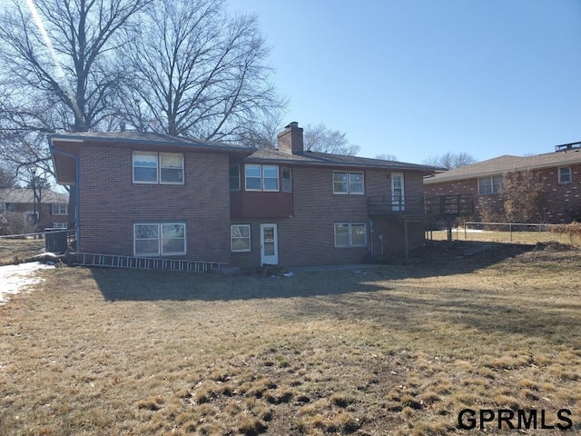 back of property featuring brick siding, a lawn, a chimney, and fence