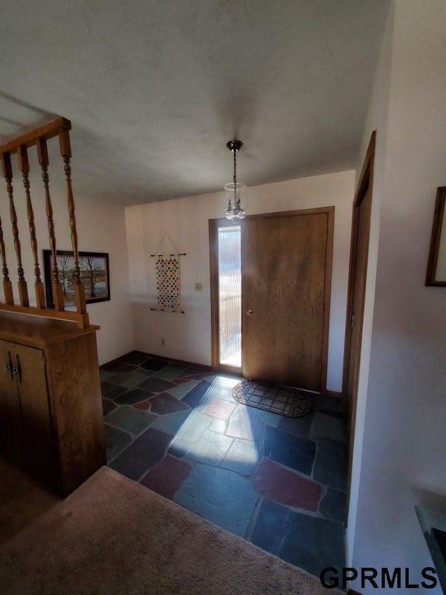 foyer entrance with stone tile flooring and an inviting chandelier