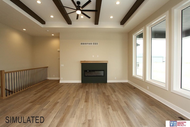 unfurnished living room featuring wood finished floors, baseboards, recessed lighting, a glass covered fireplace, and beamed ceiling