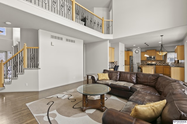 living room featuring visible vents, plenty of natural light, and stairway