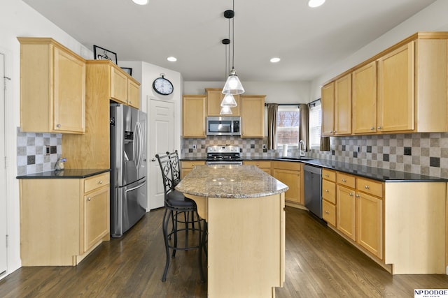 kitchen featuring dark wood-type flooring, appliances with stainless steel finishes, a center island, and light brown cabinetry