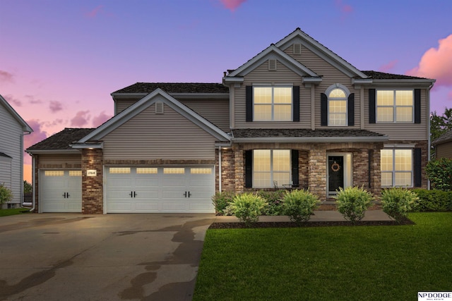 traditional-style house featuring driveway, an attached garage, and a front lawn