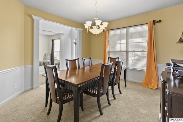 dining room with decorative columns, baseboards, a chandelier, and light carpet