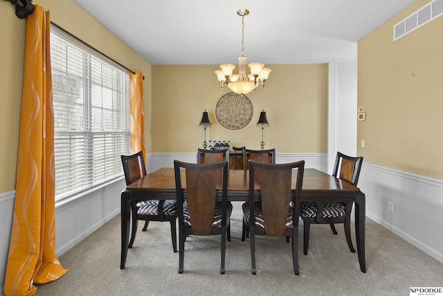 carpeted dining room with visible vents, baseboards, and a chandelier