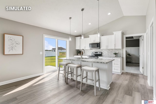 kitchen featuring a kitchen bar, an island with sink, tasteful backsplash, appliances with stainless steel finishes, and white cabinets