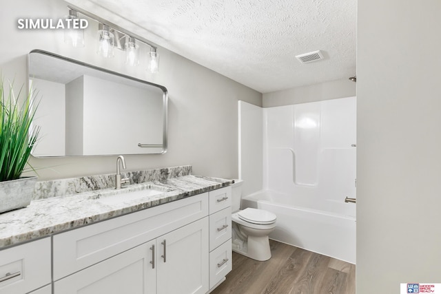 bathroom with vanity, wood finished floors, visible vents, a textured ceiling, and toilet