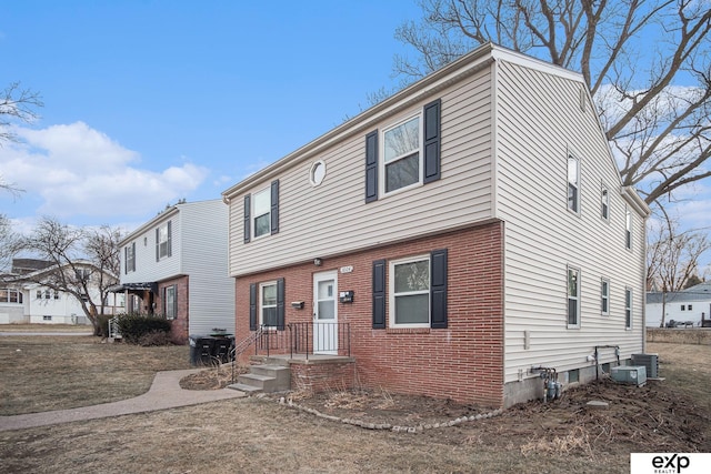 colonial-style house featuring brick siding and cooling unit