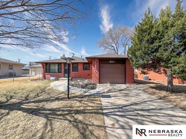 ranch-style home featuring brick siding, concrete driveway, an attached garage, and fence