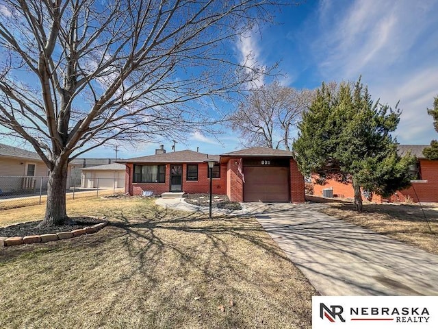 ranch-style home with fence, an attached garage, a chimney, concrete driveway, and brick siding