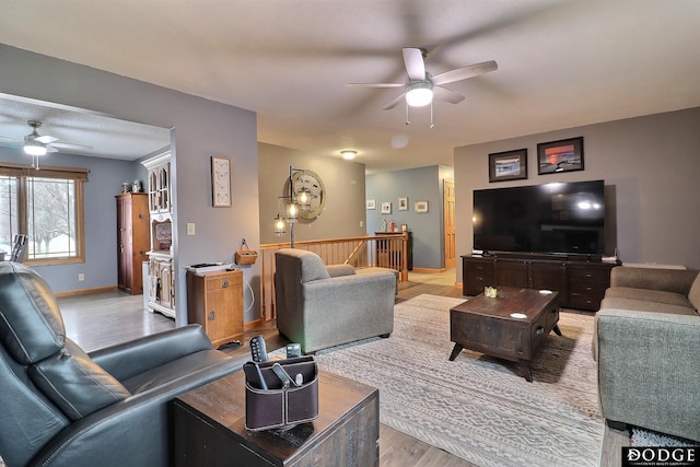 living room featuring light wood finished floors, baseboards, and a ceiling fan