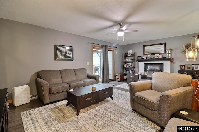 living area with a ceiling fan, wood finished floors, and a fireplace