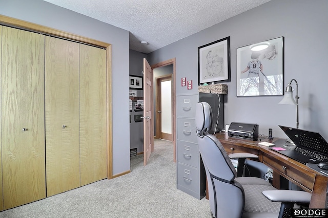 home office featuring light colored carpet, a textured ceiling, and baseboards